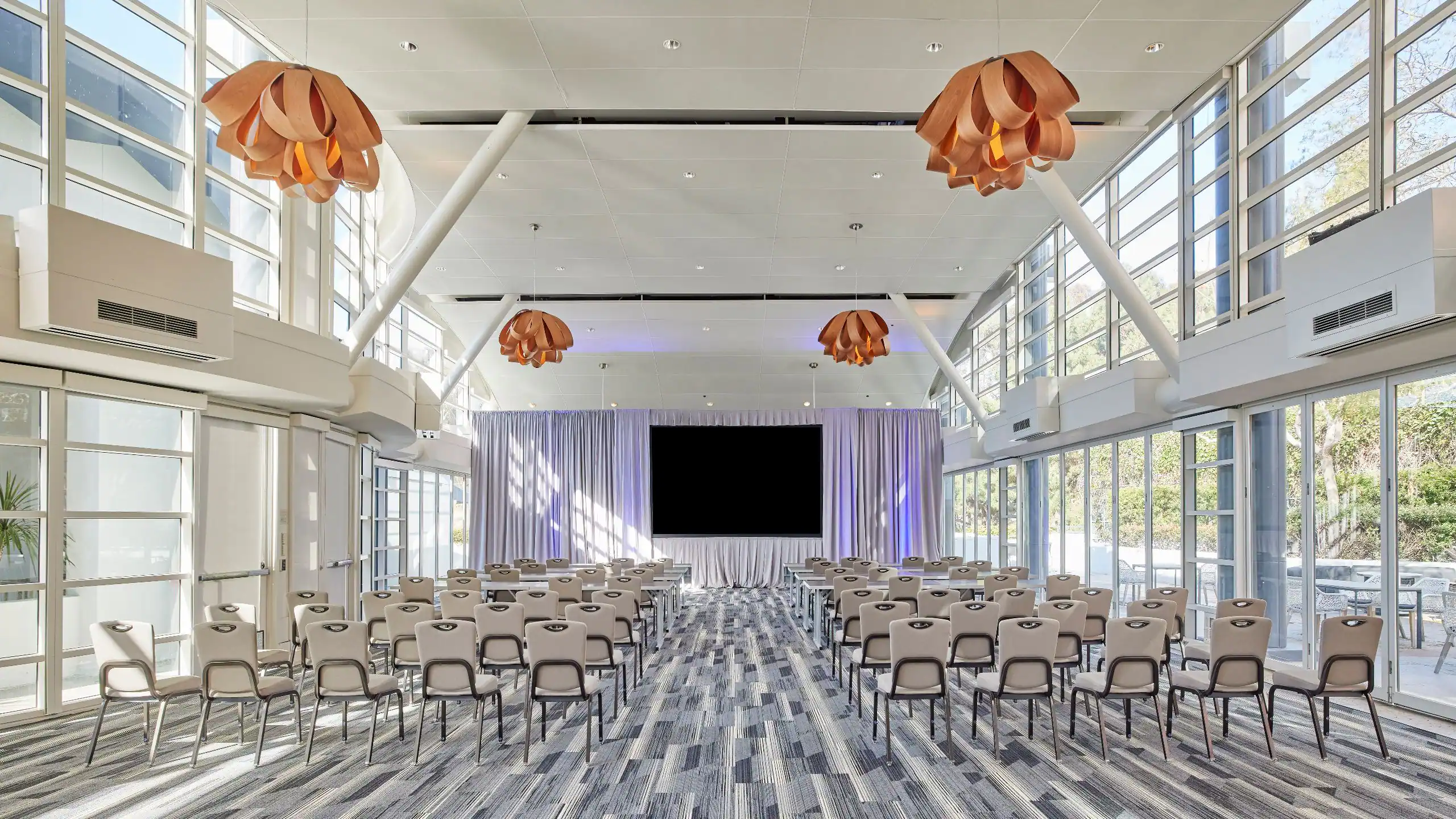 Conference pavilion in theatre layout with a presentation screen and sculptural lighting