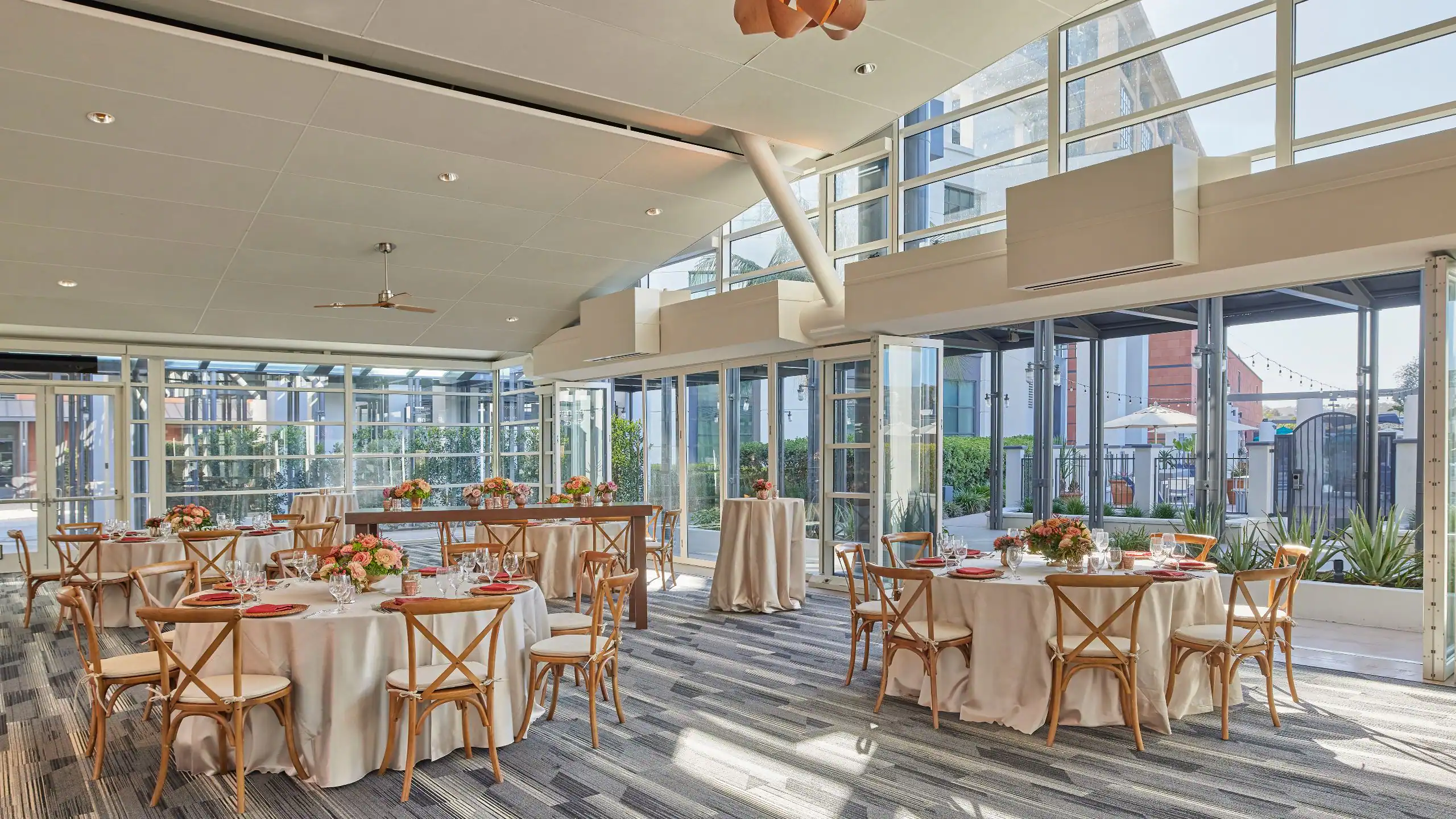 Glass-walled pavilion set for a networking reception with round banquet tables